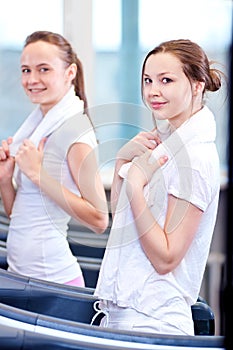 Two young sporty women run on machine