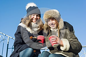 Two young teenage girls having fun outdoors, girlfriends in winter clothes, positive people and friendship concept.