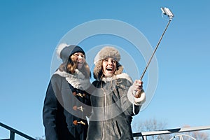 Two young teenage girls having fun outdoors, happy smiling girlfriends in winter clothes taking selfie, positive people and