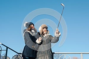 Two young teenage girls having fun outdoors, happy smiling girlfriends in winter clothes taking selfie, positive people and