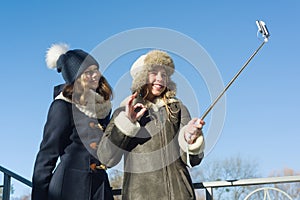 Two young teenage girls having fun outdoors, happy smiling girlfriends in winter clothes taking selfie, positive people and friend