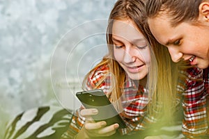 Two young teenage girls using mobile phones while sitting on a couch at home