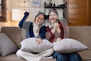 Two Young woman cheering together for sport on TV in cozy living room at home