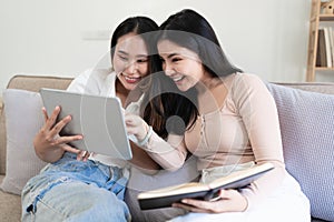 Two Young woman cheering together for sport on TV in cozy living room at home