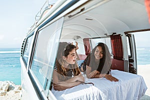 Two young woman lay down relax inside of retro van