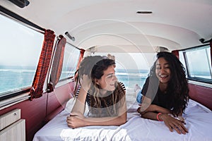 Two young woman lay down relax inside of retro van