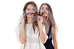 Two young woman making moustache of their hair