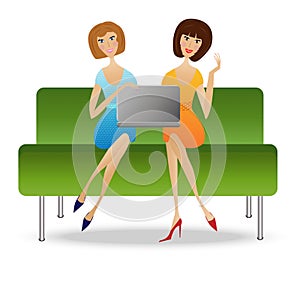 Two young woman with notebook sit on sofa