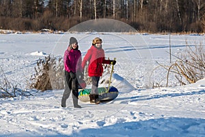 Two young woman with snow tubing winter activity, runs in winter. Winter entertainment