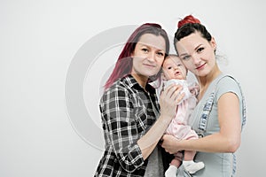 Two young women with a baby on a white background. Same-sex marriage and adoption, homosexual lesbian couple.