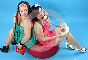 Two young women calling on phones on blue background