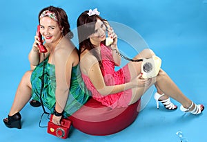 Two young women calling on phones on blue background