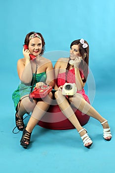 Two young women calling on phones on blue background