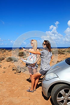 Two young women with car look at map