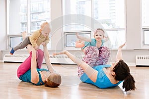 Two young women with children doing workout in gym class to loose baby weight.