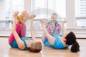 Two young women with children doing workout in gym class to loose baby weight.