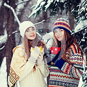 Two young women with colorful cups drinking tea outdoor and smiling