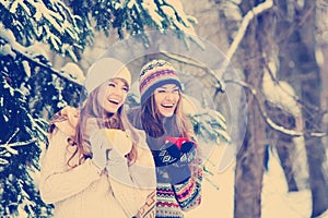 Two young women with colorful cups drinking tea outdoor and smiling