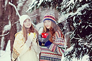 Two young women with colorful cups drinking tea outdoor and smiling