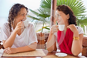 Two young women with cups sitting in an arbour photo