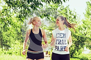 Two young women doing sports outdoors in a park on sunny summer