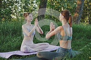 Two young women doing yoga anjali mudra outdoors, mental health care