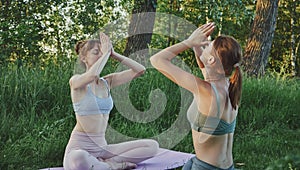 Two young women doing yoga anjali mudra outdoors, mental health care