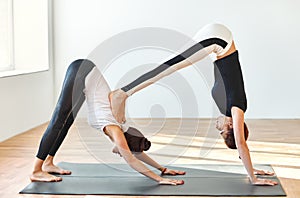 Two young women doing yoga asana double downward dog