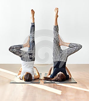 Two young women doing yoga asana supported shoulderstand