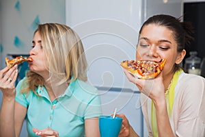 Two young women eat pizza. Girls taste italian traditional food