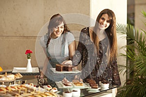 Two young women enjoying a dessert buffet