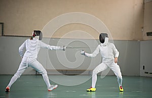 Two young women fencers having a training at the gym