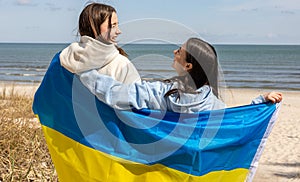 Two young women with the flag of Ukraine on the background of the sea.