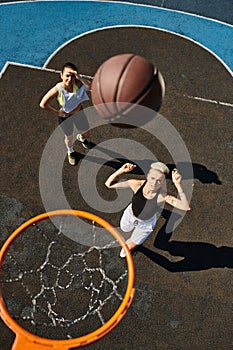 Two young women, friends, playing basketball