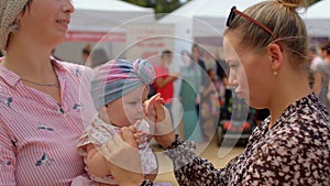 Two young women with a happy child in a public place, closeness baby to mother.