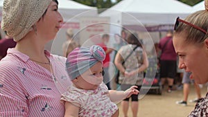 Two young women with a happy child in a public place, closeness baby to mother.