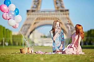 Two young women having picnic near the Eiffel tower in Paris, France