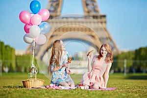 Two young women having picnic near the Eiffel tower in Paris, France