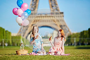 Two young women having picnic near the Eiffel tower in Paris, France