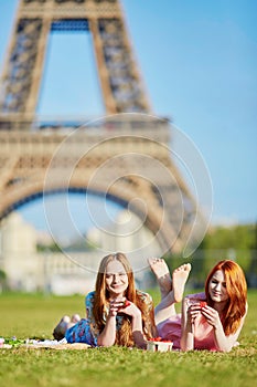 Two young women having picnic near the Eiffel tower in Paris, France