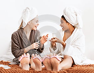 Two young women having spa day together, drinking champagne