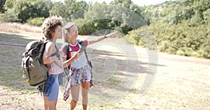 Two young women are hiking, one pointing out a direction with copy space