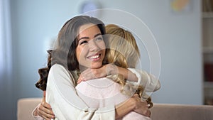 Two young women hugging and sincerely smiling, true old friendship, indoors