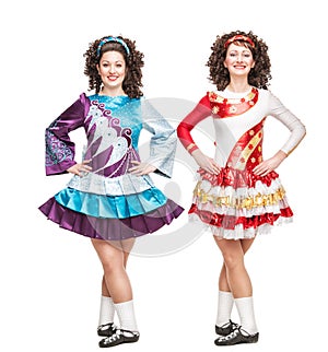 Two young women in Irish dance dresses posing isolated