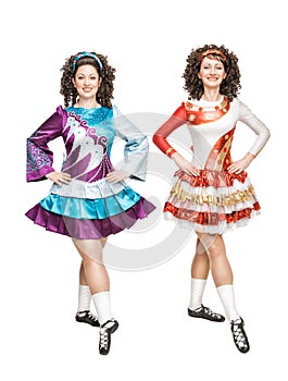 Two young women in Irish dance dresses posing isolated