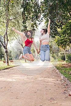 two young women jumping with joy holding hands