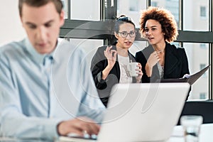 Two young women laughing behind their male colleague