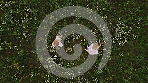 Two young women in light summer dresses dancing in the field