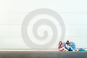 Two young women listening to music on smartphones far shot