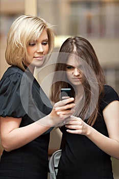 Two young women looking at a cell phone